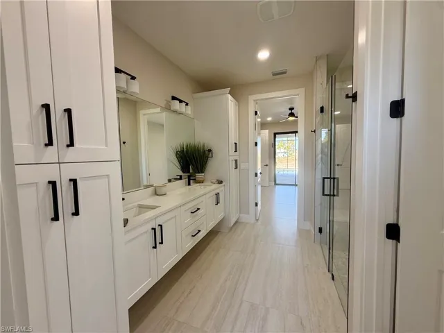 Bathroom with double vanity, a shower stall, a ceiling fan, and recessed lighting
