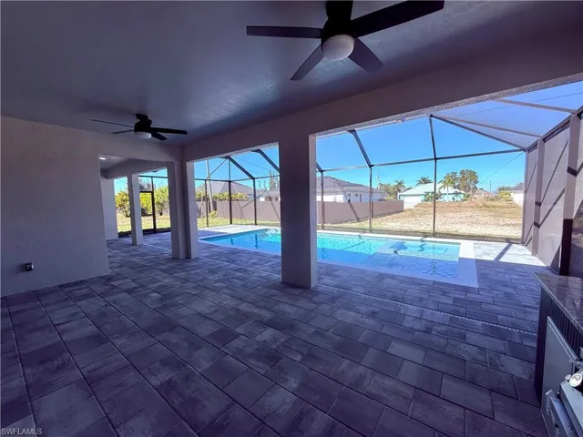 View of pool with a sunroom, patio surround, and glass enclosure