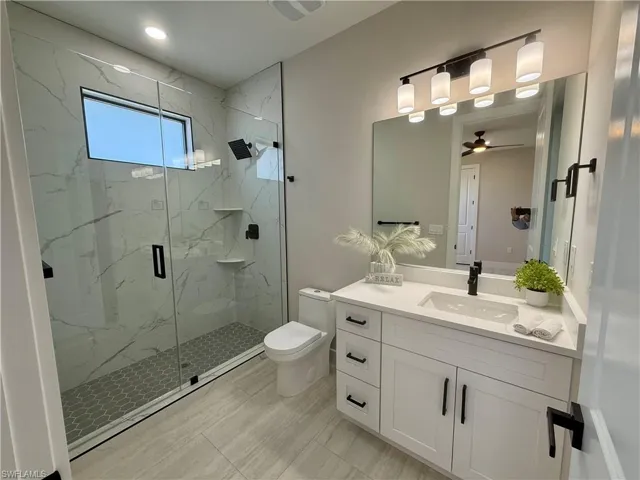 Full bathroom featuring vanity, a marble finish shower, and a ceiling fan