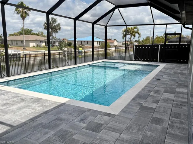 View of pool featuring a water view, glass enclosure, a fenced backyard, and a sunroom