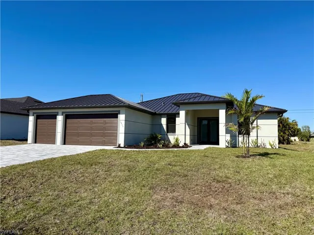 View of front of home featuring a standing seam roof, a front lawn, decorative driveway, an attached garage, and stucco siding