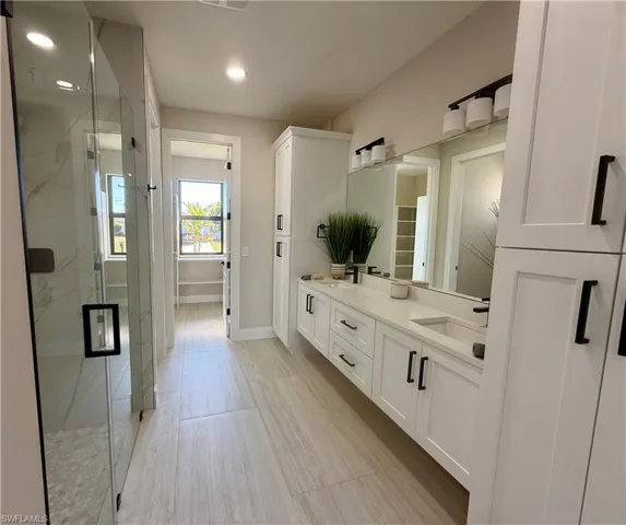 Full bathroom with double vanity, a marble finish shower, and recessed lighting