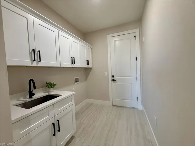 Laundry area with hookup for a washing machine, cabinet space, and light wood-type flooring
