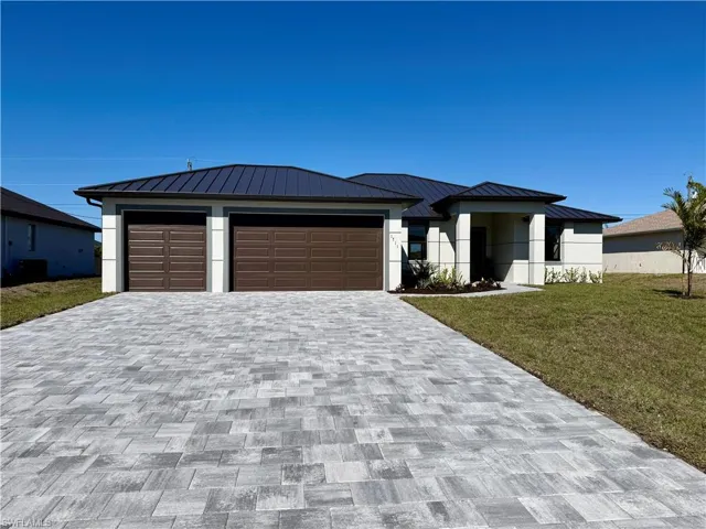 View of front of home featuring a front lawn, decorative driveway, and stucco siding