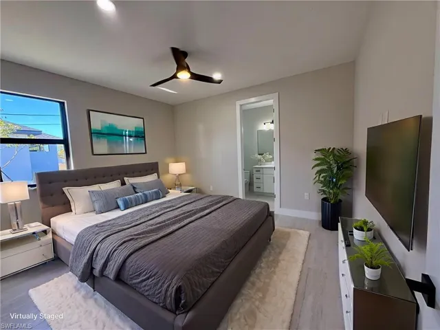 Bedroom with ceiling fan, light wood-type flooring, and ensuite bath