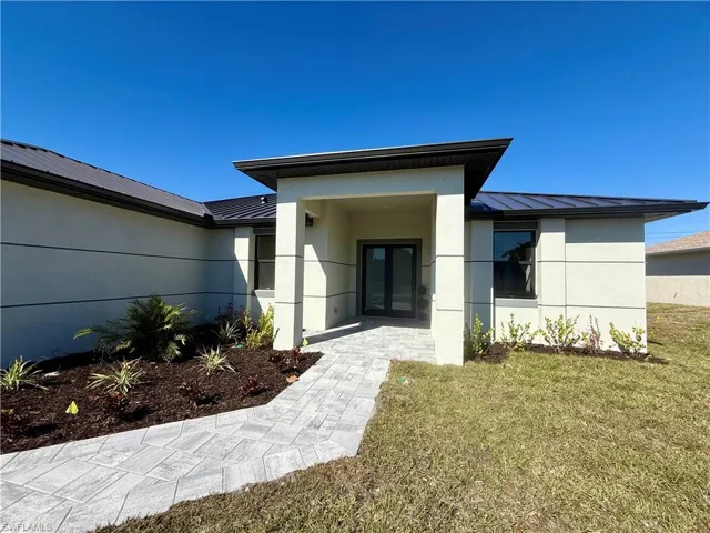 Property entrance featuring a standing seam roof, stucco siding, a yard, and french doors