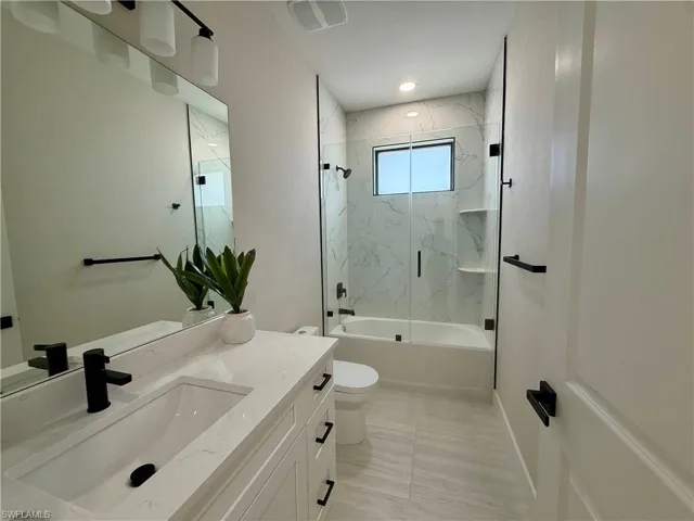 Full bath featuring vanity, enclosed tub / shower combo, and recessed lighting