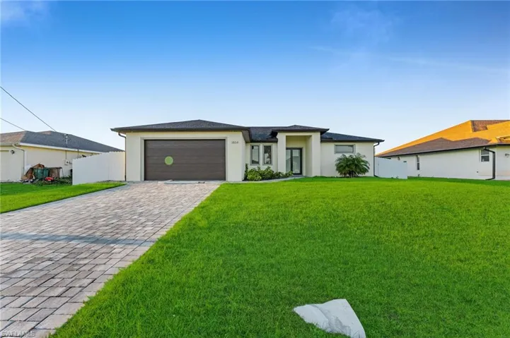 Prairie-style house featuring stucco siding, a front yard, a garage, and driveway
