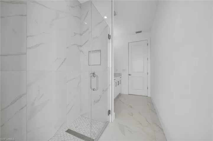 Full bath with a marble finish shower, visible vents, marble finish floor, and baseboards