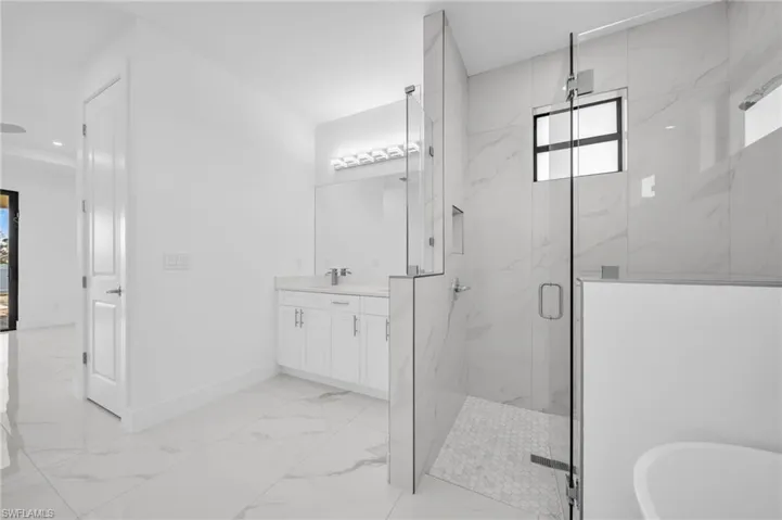 Full bathroom with a marble finish shower, baseboards, a freestanding bath, marble finish floor, and vanity