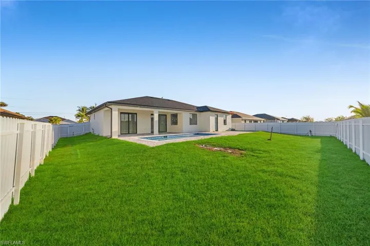 Rear view of property featuring a yard, a fenced backyard, and stucco siding