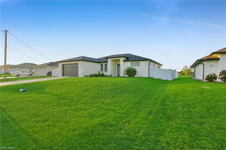 View of front of home with stucco siding, a front lawn, concrete driveway, and a garage