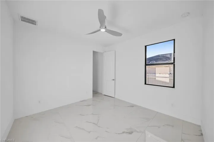 Spare room with baseboards, visible vents, marble finish floor, and ceiling fan
