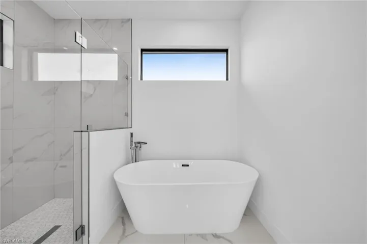 Full bath featuring a freestanding tub, marble finish floor, and a marble finish shower