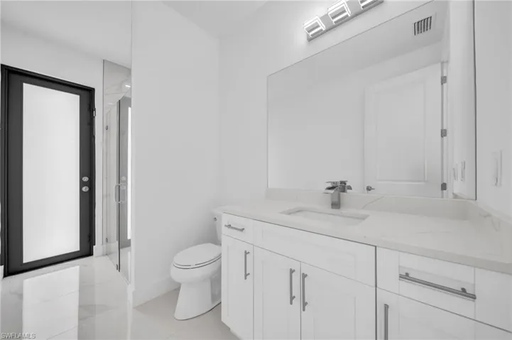 Bathroom featuring visible vents, toilet, a stall shower, and vanity