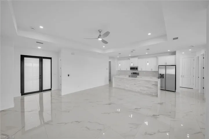 Unfurnished living room with visible vents, a raised ceiling, marble finish floor, and ceiling fan