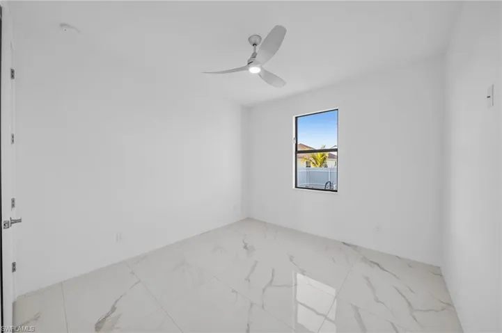 Unfurnished room with marble finish floor and a ceiling fan