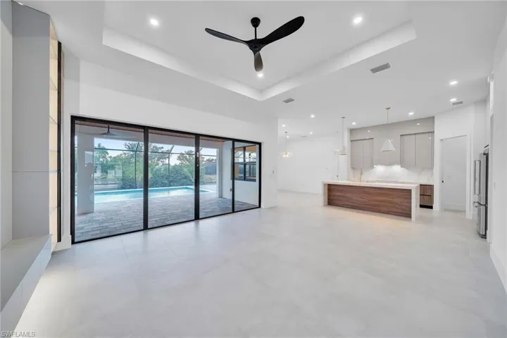 Unfurnished living room featuring ceiling fan, a tray ceiling, and recessed lighting