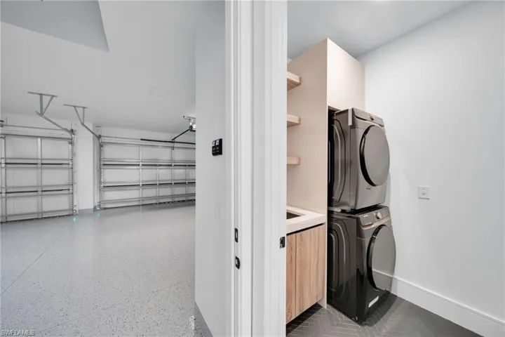 Laundry area featuring stacked washer / dryer, a garage, and dark speckled floor