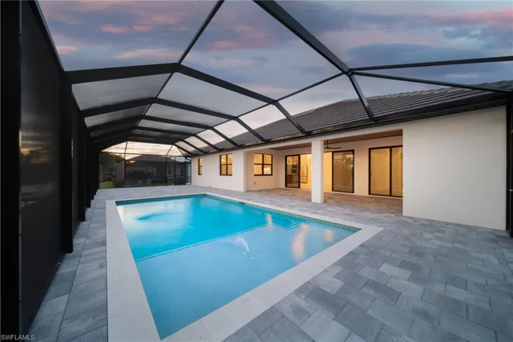 Pool at dusk featuring a sunroom, an outdoor pool, a patio area, and a lanai
