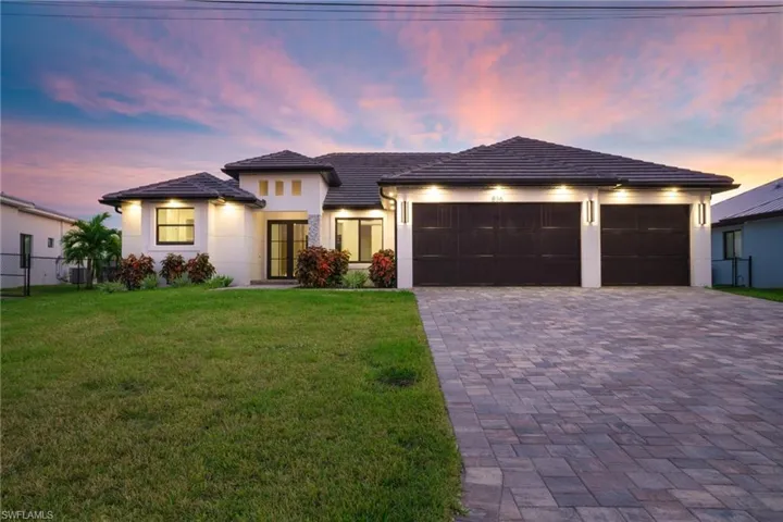 View of front of home with a garage, driveway, stucco siding, and a tile roof