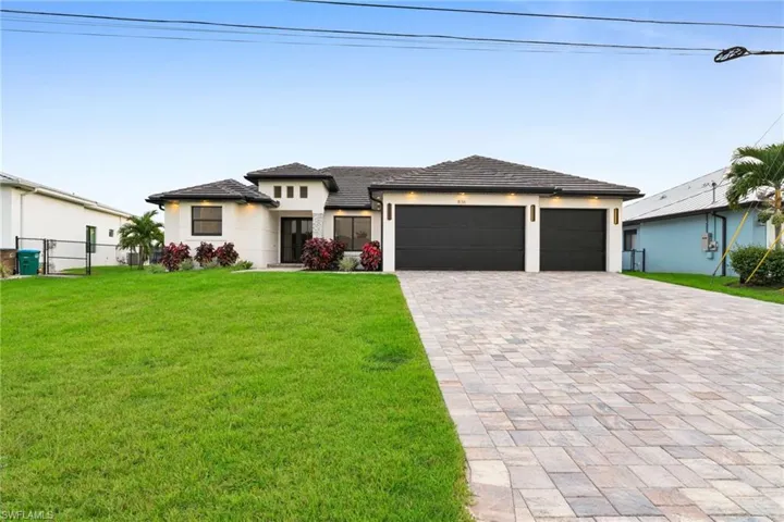Prairie-style house with an attached garage, decorative driveway, and stucco siding