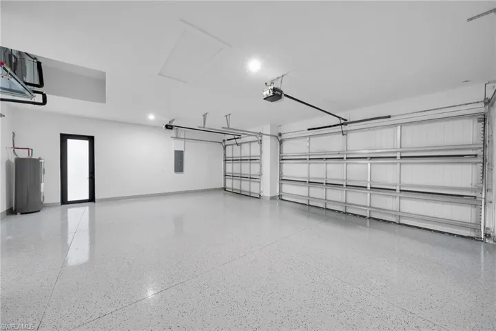 Garage featuring water heater, electric panel, and a garage door opener