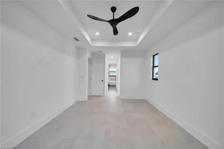 Empty room featuring ceiling fan, recessed lighting, a tray ceiling, and concrete floors