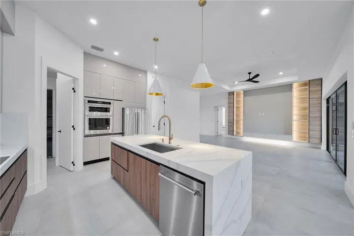 Kitchen with modern cabinets, open floor plan, a center island with sink, two tone color scheme, and stainless steel appliances