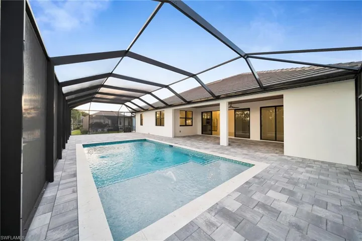 Outdoor pool with a sunroom, a patio area, and glass enclosure