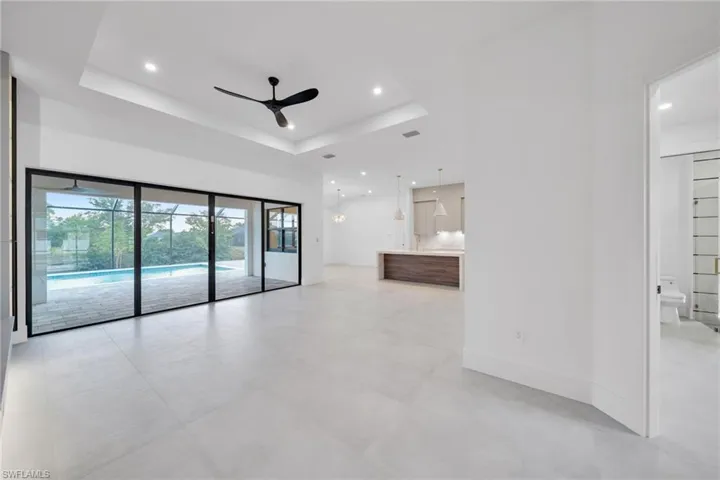 Unfurnished living room featuring ceiling fan, recessed lighting, and a raised ceiling