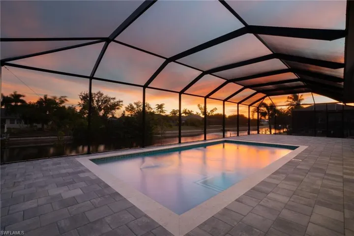 Pool at dusk with an outdoor pool and a sunroom