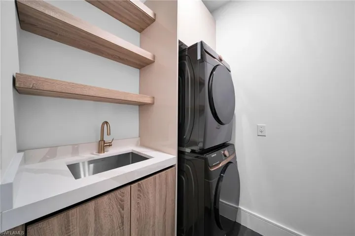 Laundry area featuring stacked washer and dryer and cabinet space