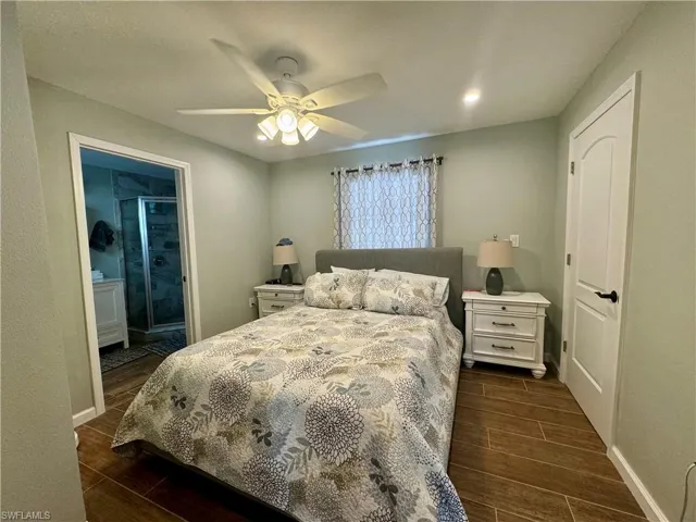 Bedroom with ensuite bath, dark wood-type flooring, and ceiling fan