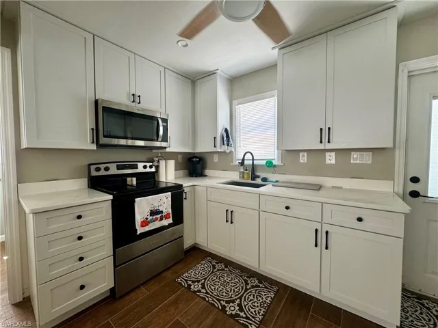 Kitchen with white cabinetry, appliances with stainless steel finishes, sink, and dark hardwood / wood-style flooring