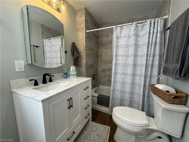 Full bathroom featuring vanity, toilet, shower / tub combo with curtain, and hardwood / wood-style floors