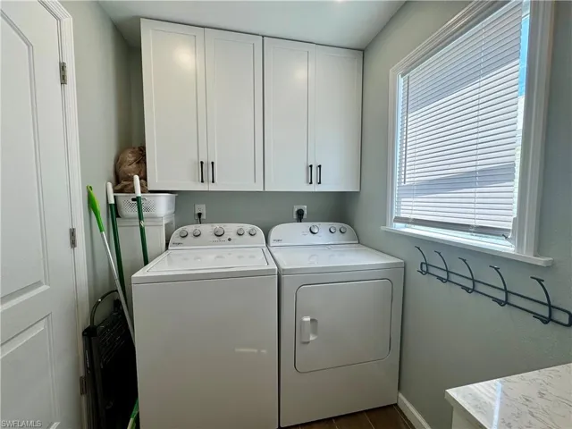Washroom with cabinets, dark wood-type flooring, plenty of natural light, and washing machine and clothes dryer