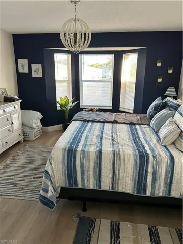 Bedroom with wood finished floors, a textured ceiling, and a chandelier