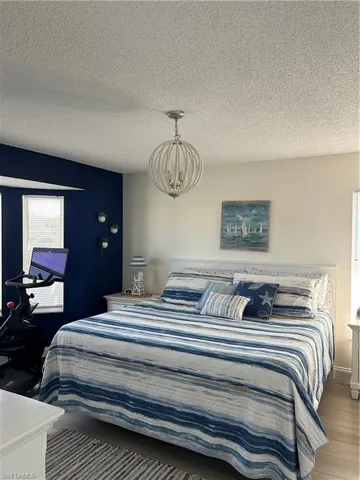 Bedroom with a textured ceiling, a chandelier, and wood finished floors