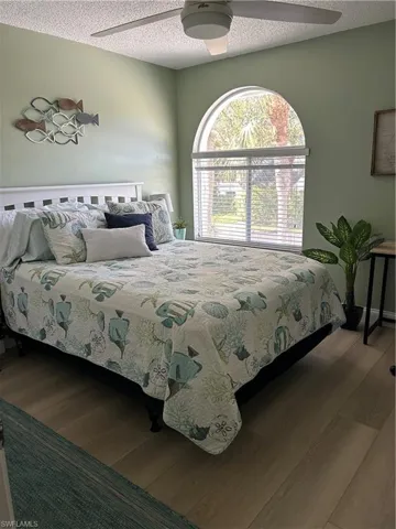 Bedroom featuring wood finished floors, a textured ceiling, and a ceiling fan