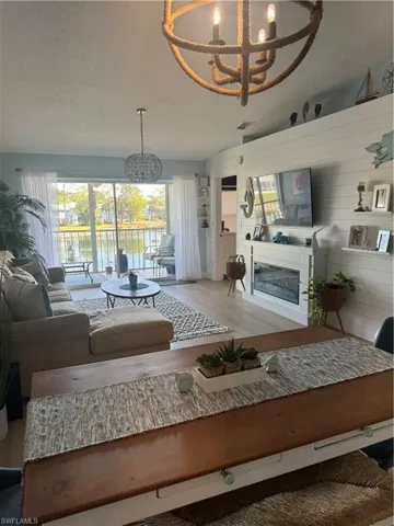 Living room with a textured ceiling, a chandelier, a glass covered fireplace, and wood finished floors