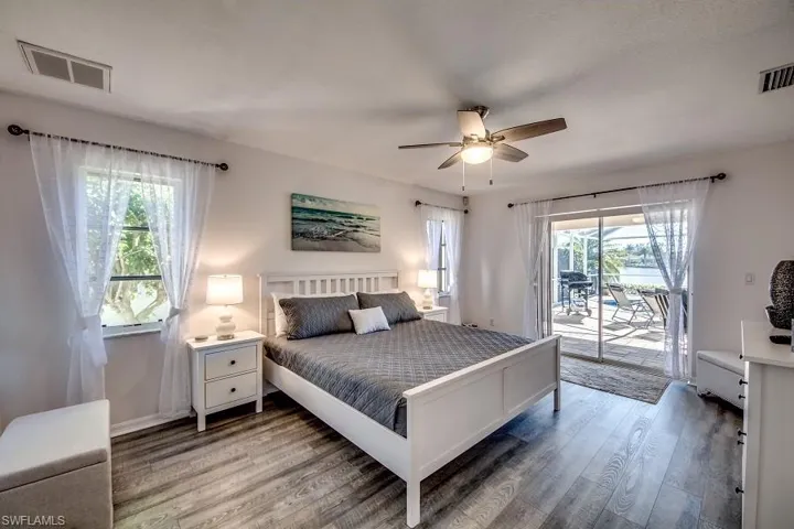 Bedroom featuring access to exterior, wood-type flooring, multiple windows, and ceiling fan