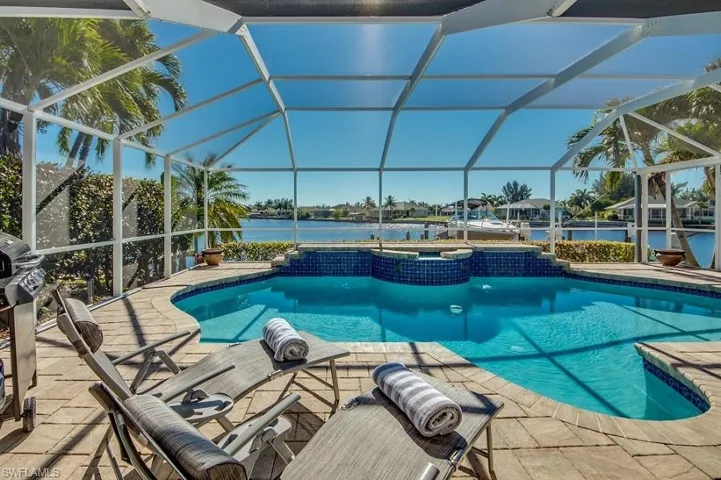 View of swimming pool featuring a water view, glass enclosure, and a patio area