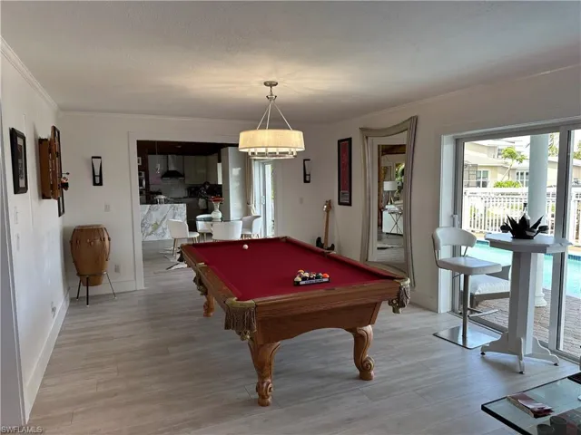 Recreation room featuring pool table, light wood-style floors, crown molding, and a textured ceiling