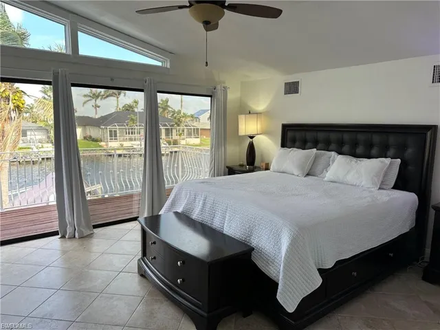 Bedroom with lofted ceiling, a water view, access to outside, ceiling fan, and light tile patterned floors