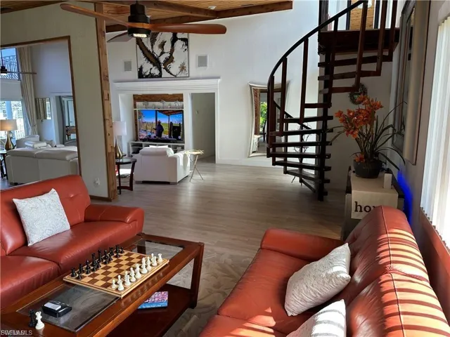 Living room with ceiling fan, wood finished floors, and a high wood beamed ceiling