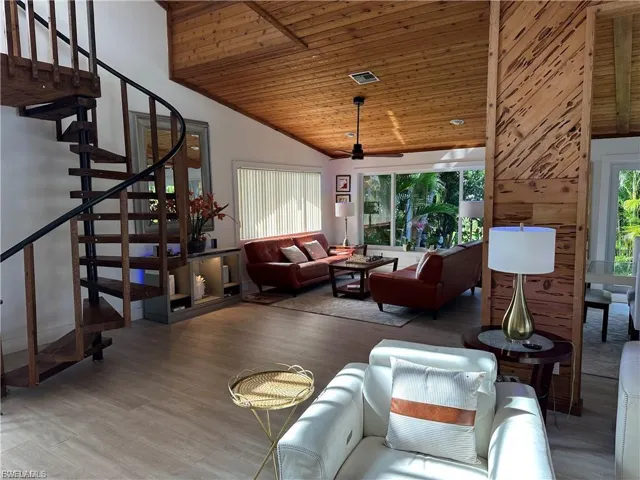 Living area with a vaulted wood ceiling, wood finished floors, and ceiling fan