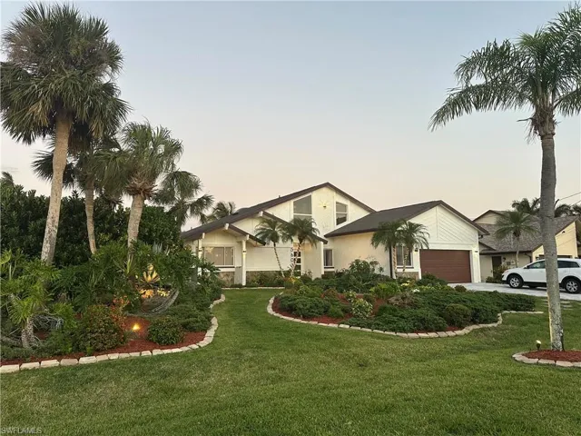 View of front of home with a front lawn, a garage, driveway, and stucco siding