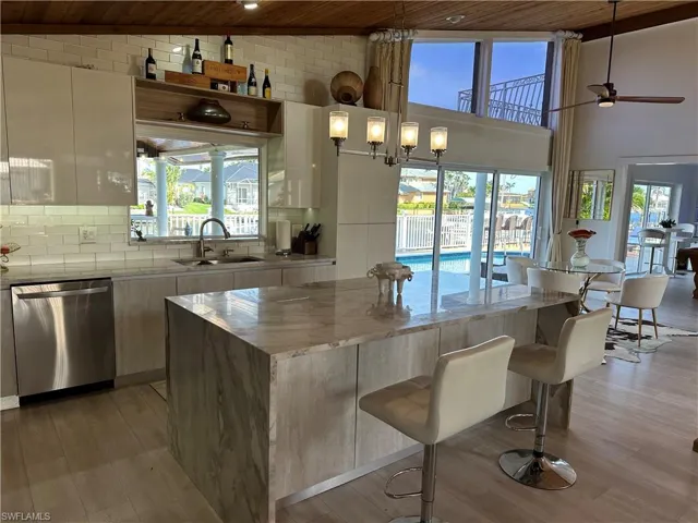 Kitchen featuring a vaulted wooden ceiling, light stone counters, stainless steel dishwasher, modern cabinets, and light wood-style floors