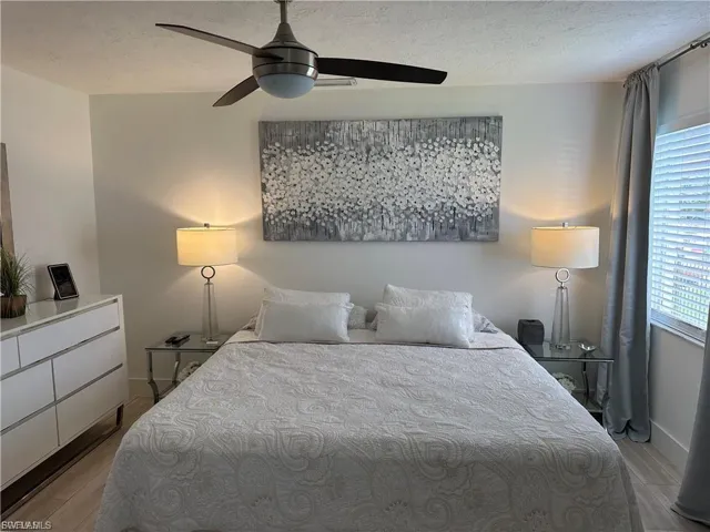 Bedroom featuring a textured ceiling, light wood-style floors, and a ceiling fan